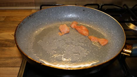 poner rodajas de pechuga de pollo cruda en una sartén caliente para preparar la cena