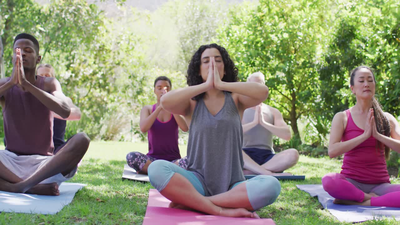 grupo de jóvenes diversos meditando y practicando yoga juntos en el parque