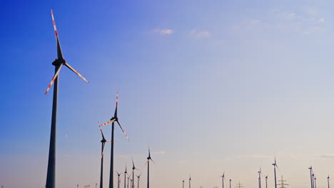 wind turbines stand tall against the sky. numerous wind turbines spin gently in a clear sky during a bright, sunny day, showcasing renewable energy in action