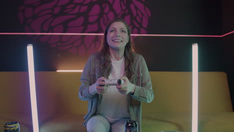 excited girl playing video games sitting on sofa at home