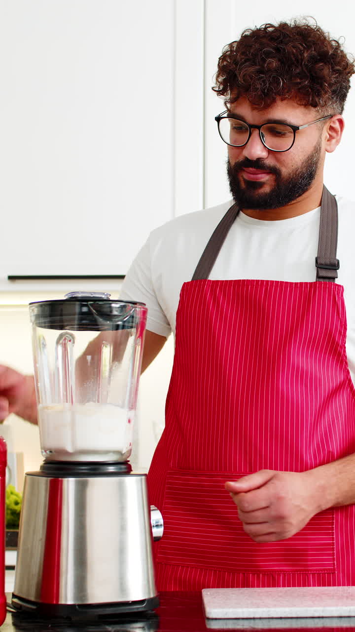 Giovane adulto arabo che frulla un frullato di proteine del siero del latte con banana e mela per il fitness nella cucina di casa