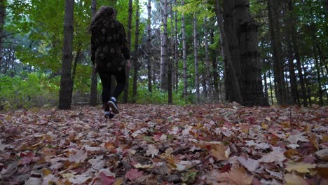 low angle woman walking over leaf-covered trail in forest