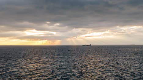 sun rays piercing through clouds over the ocean near genoa with ships on the horizon, aerial hyperlapse