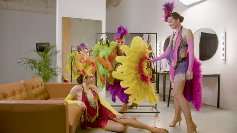 three showgirls having fun with a feather fan