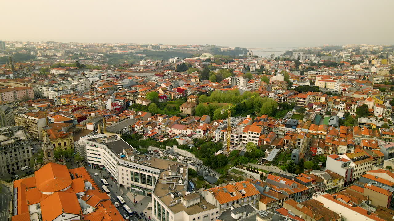 Densely populated residential area with recognizable orange roofs between green nature on the Portuguese hills built in the large city of Porto on a cloudy day