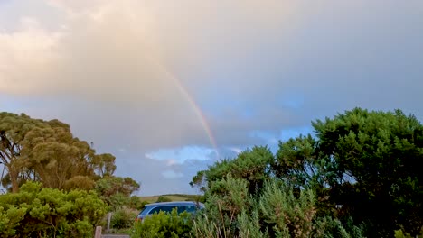 a vibrant rainbow arcs over a lush, green landscape in australia, captured under soft, natural lighting