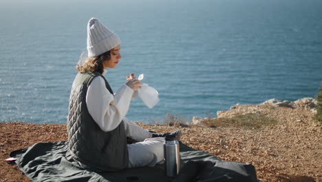 Niña-Comiendo-Picnic-En-El-Océano-Solo-En-El-Borde-Del-Acantilado.-Turista-Sereno-Admirar-El-Paisaje