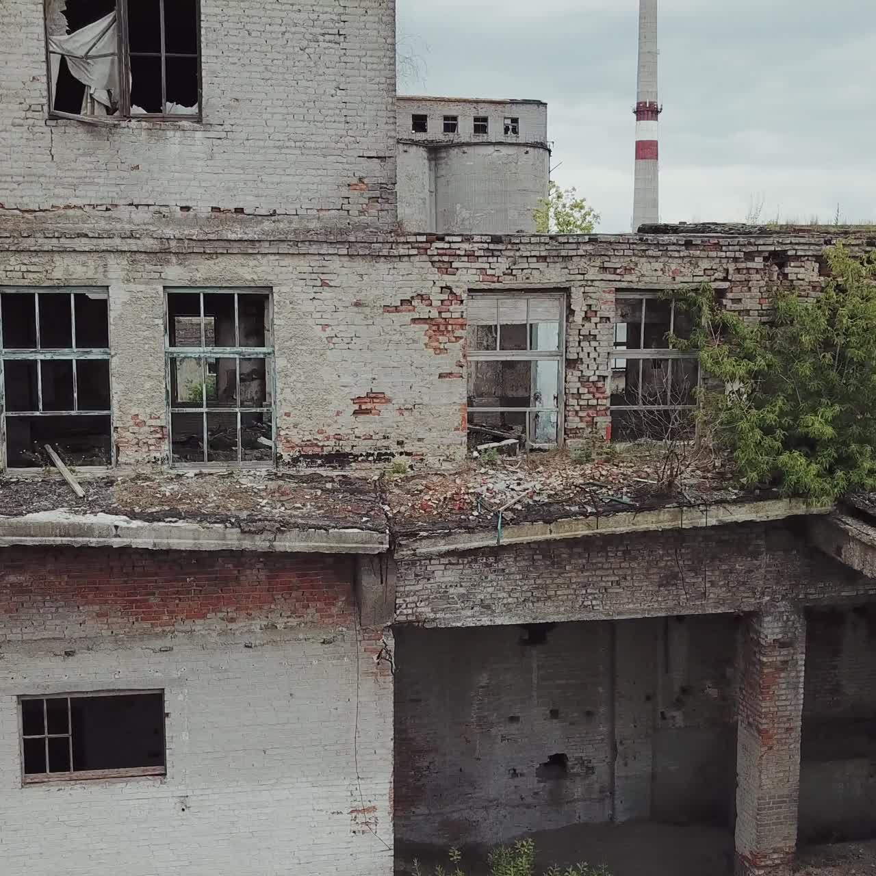 Aerial view of abandoned industrial buildings. Abandoned factory halls with broken glass on windows.