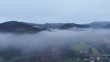 Overcast-bleak-sky-and-mist-cloud-over-hilly-countryside-landscape