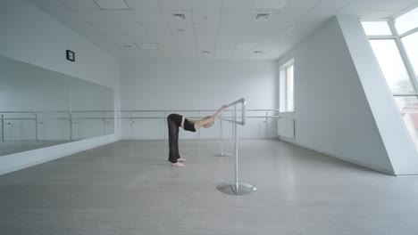 fit girl in black clothes performing contemporary. female dancer shows flowing motions, body and hands waves at white room. modern ballet dance choreography. young woman is moving smoothly