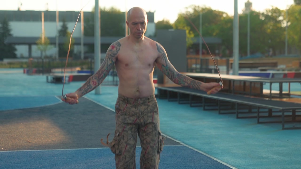 Mand uden trøje med tatoveringer sjipper i slow motion