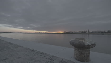 timelapse de la puesta de sol cerca del río schelde en amberes filmado desde el muelle con una roca en el primer plano