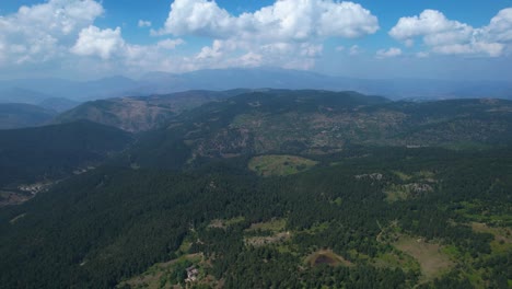 Nubes-Blancas-Danzan-Sobre-Vastas-Cadenas-Montañosas,-Cubriendo-Un-Sereno-Bosque-De-Majestuosos-Pinos-En-El-Abrazo-De-La-Naturaleza-Voskopoja.