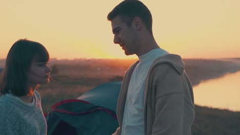 girl talks with boyfriend near tent and friends in camp