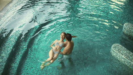 Top-view-couple-enjoying-pool-at-spa-hotel.-Couple-resting-in-pool-at-spa