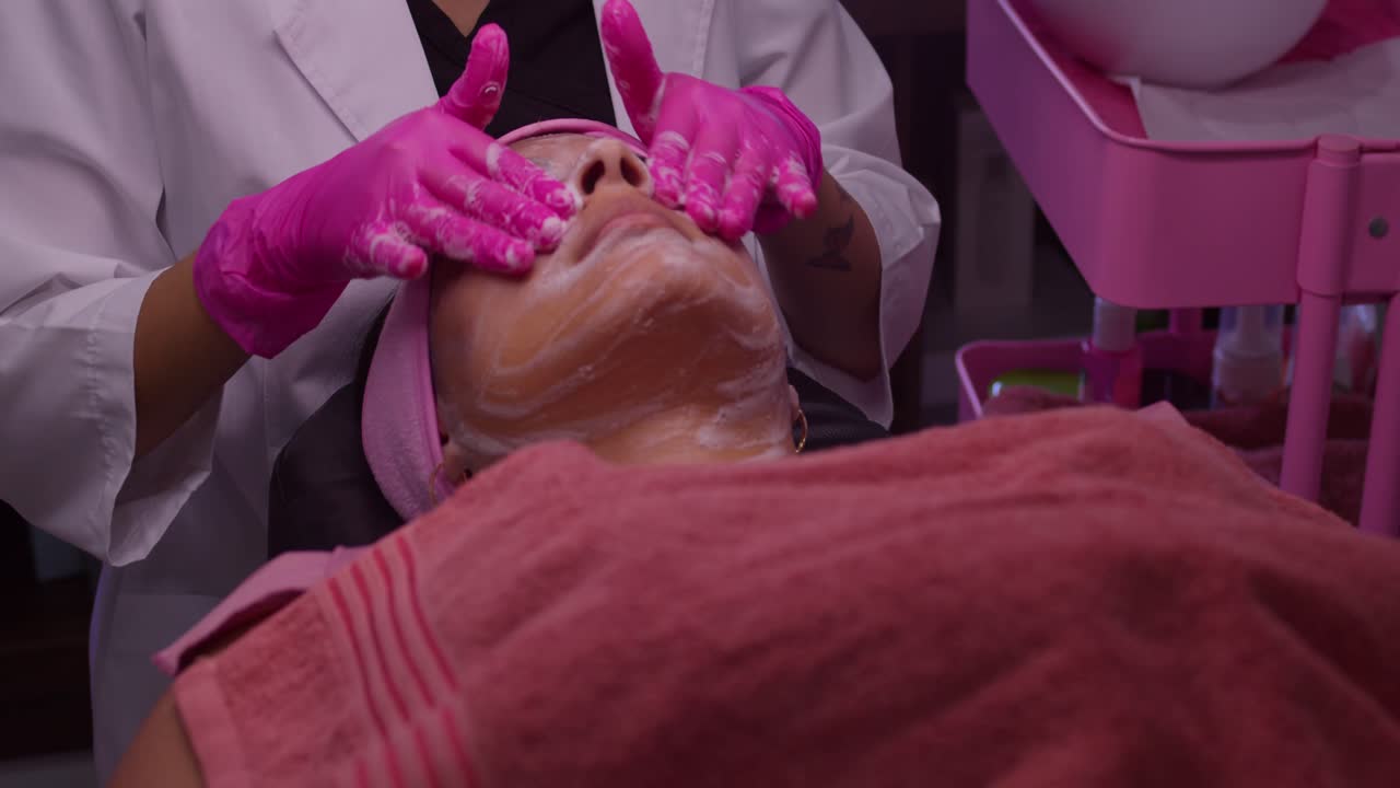 una mujer joven recibe un masaje facial en un spa de belleza