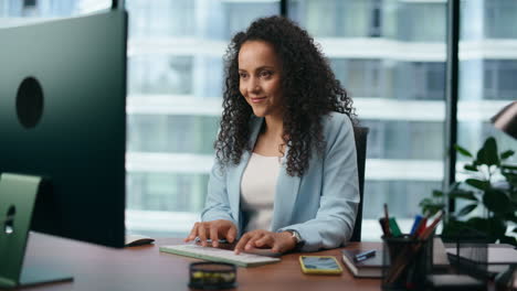 latin businesswoman sitting office desk reading good news at computer close up.