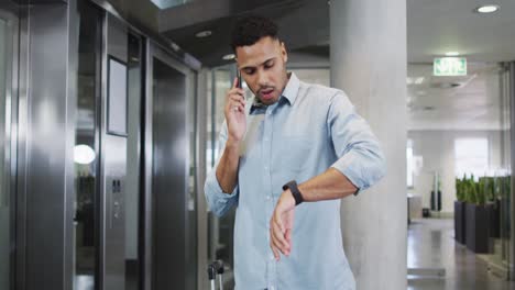 Video-De-Un-Hombre-De-Negocios-Birracial-Usando-Un-Teléfono-Inteligente-Y-Revisando-El-Reloj