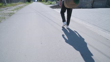 young man walking with guitar on street near forest