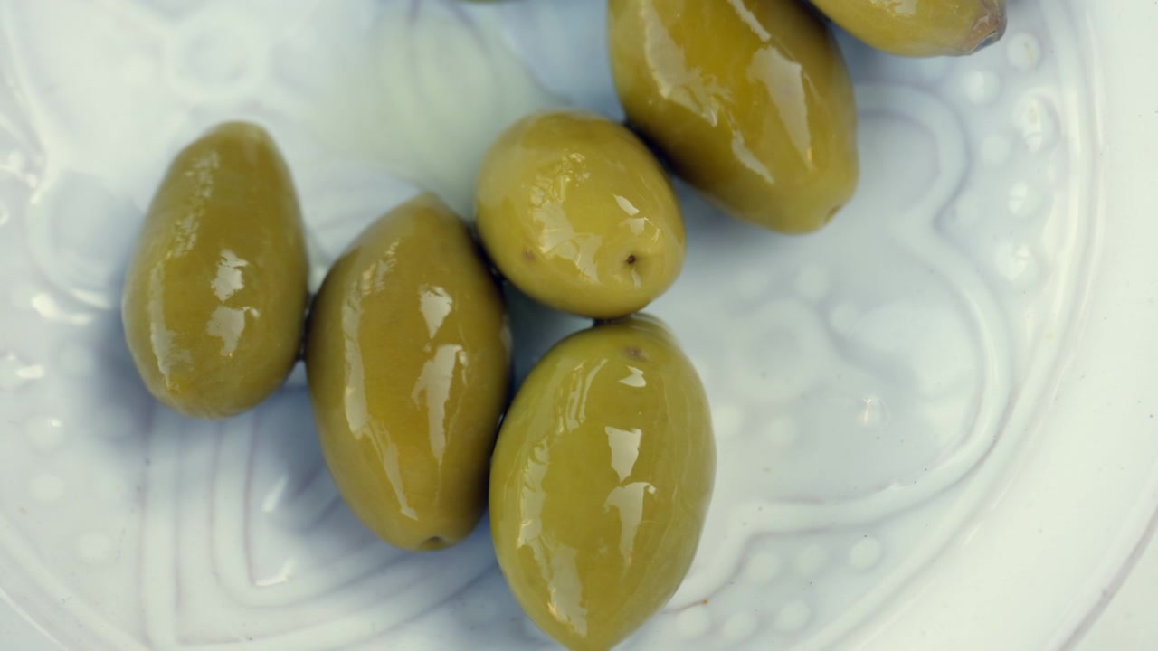 Olive verdi fresche su un piatto di ceramica bianco, uno spuntino o antipasto ideale che promuove una sana dieta mediterranea
