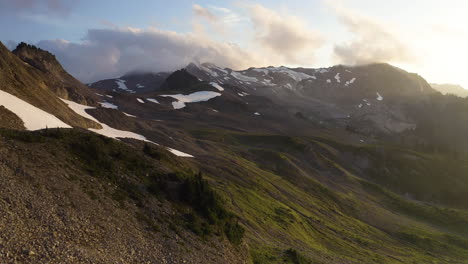 El-Dron-Asciende-Por-Una-Silla-Rocosa-En-La-Montaña-Para-Establecer-Una-Suave-Luz-Dorada-Que-Se-Extiende-Sobre-La-Nieve-Y-La-Pradera-De-Hierba-A-La-Hora-Dorada.