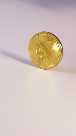 slow motion footage of a gold bitcoin coin spinning upright on a white surface, capturing the detailed engravings and reflective movement of the cryptocurrency in motion.