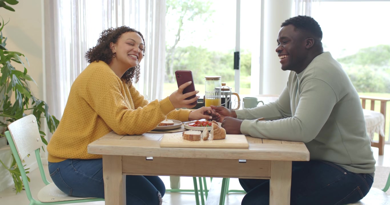 African American couple sharing woman showing phone man reaching holding hands at table with carafe