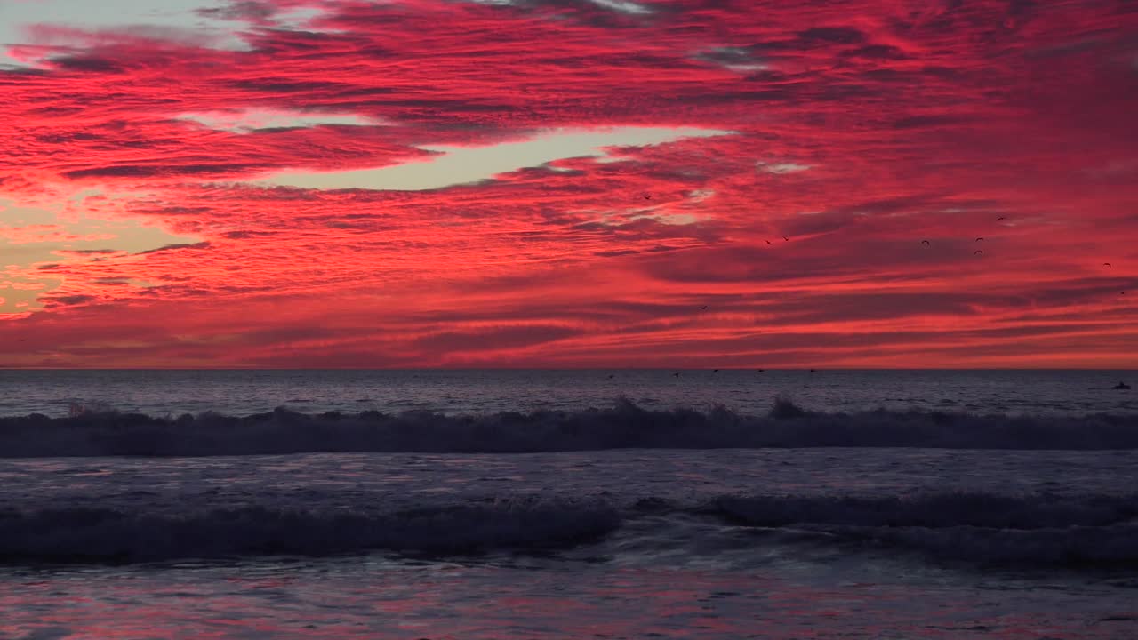 zoom de un atardecer rojo sangre que revela el océano de california