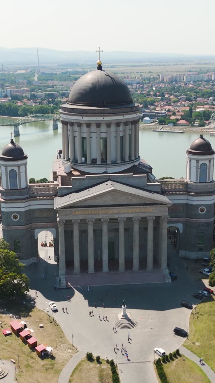 Smooth aerial pull-back from Esztergom Basilica in Hungary, revealing the Danube River and surrounding scenery, Vertical Shot
