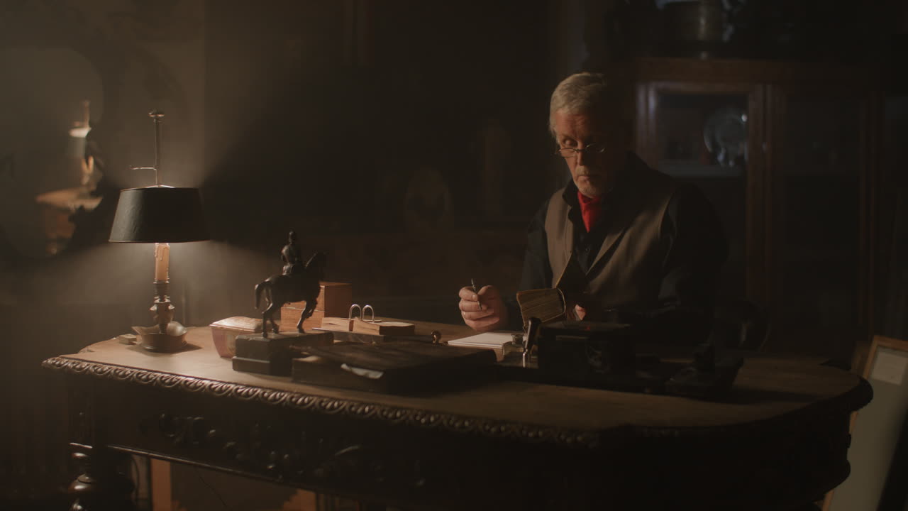 Old passionate man writes down a note in his office at night