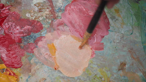 close up of an artist's palette with paint and a brush