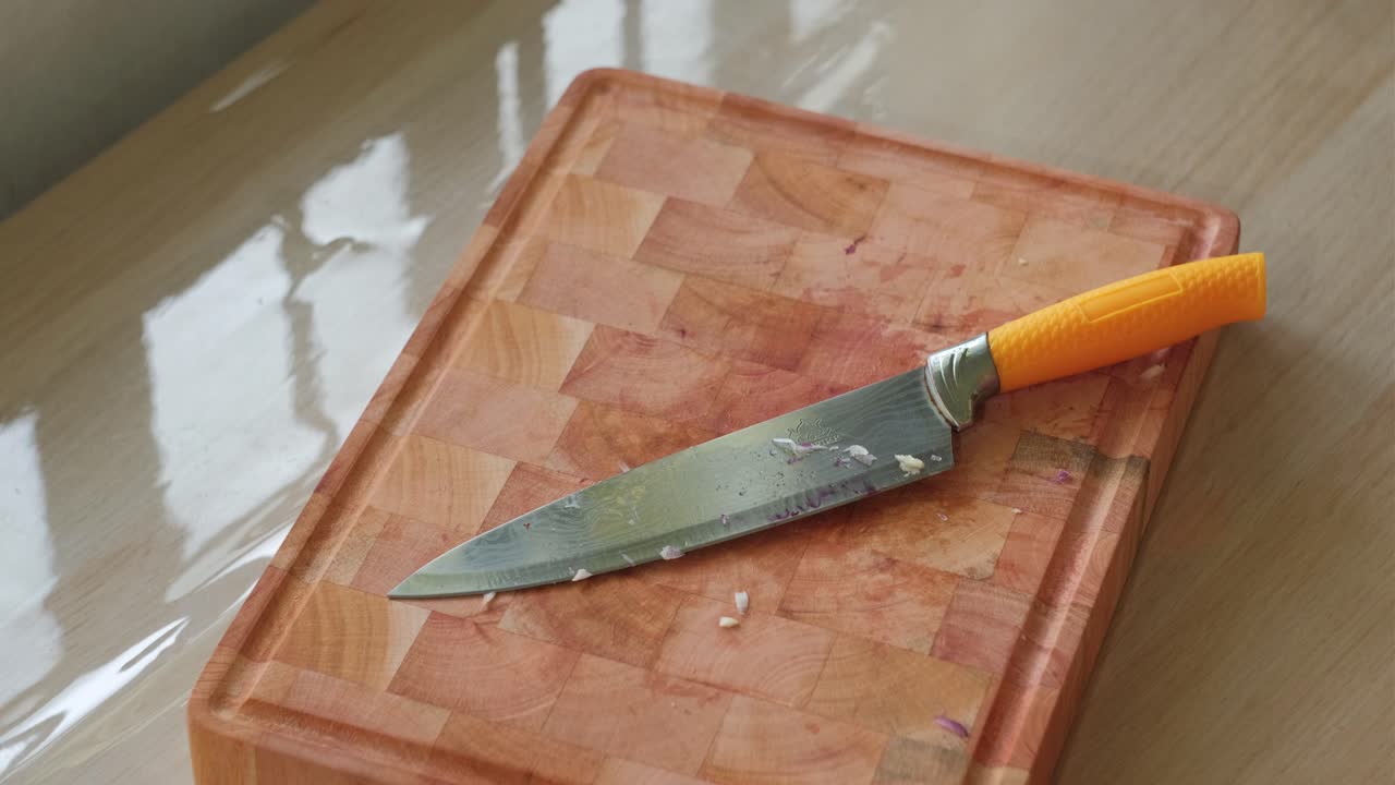 Placing Sharp Knife on Wooden Chopping Board – Static Shot