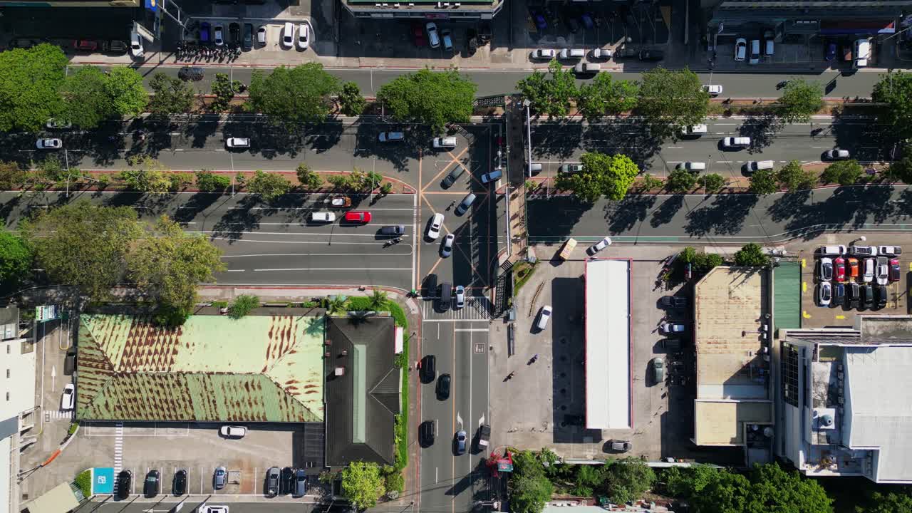 Aerial top-down view of busy traffic with cars driving along a three-way intersection and gas station at Ortigas Avenue, Greenhills, Metro Manila, Philippines.