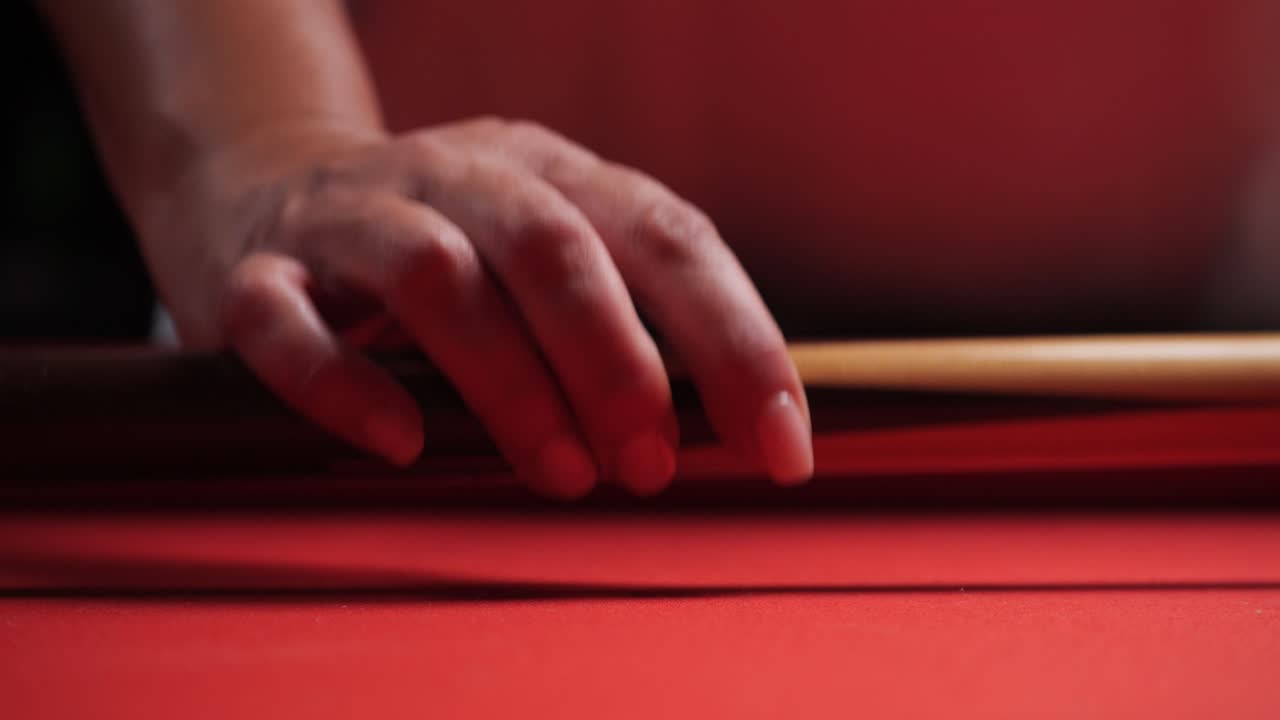 mujer camina hasta la mesa de billar roja y recoge el palo de taco de cerca