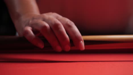 woman walks up to red billiards pool table and picks up cue stick close up