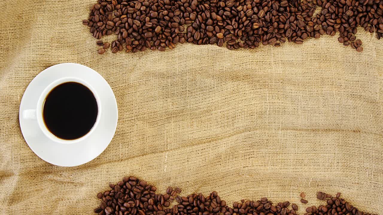 Kaffekop med kaffebønner arrangeret på sæk