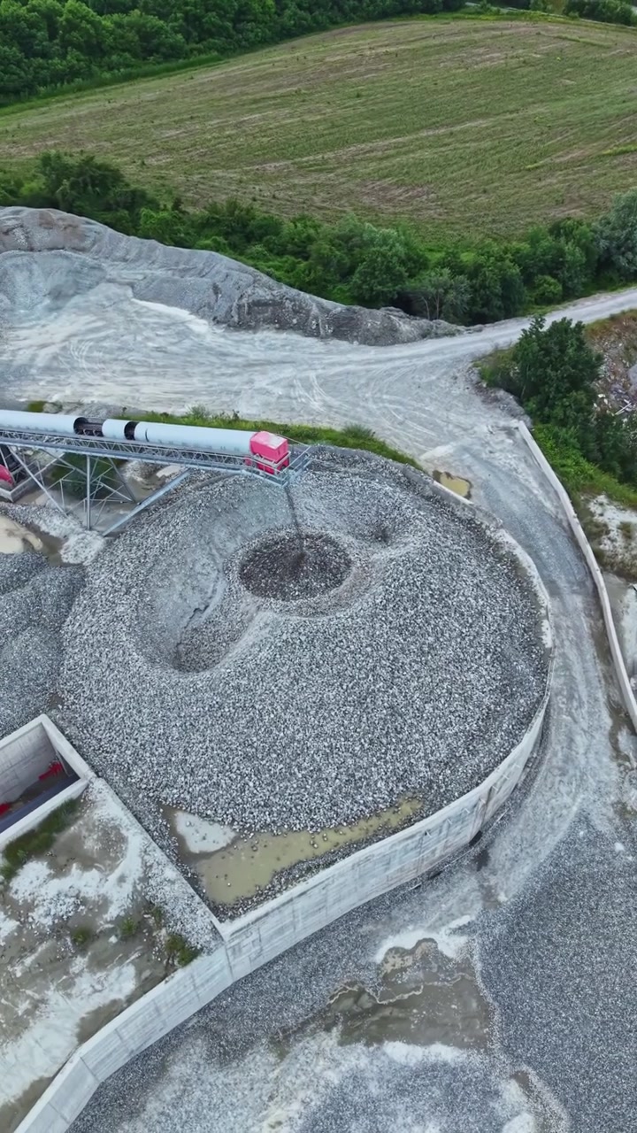 Granite quarry operations show conveyor system transporting stones from extraction site to processing area for construction materials