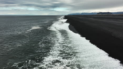 drone shot flying along the stokksnes black sand beach, cloudy evening in iceland