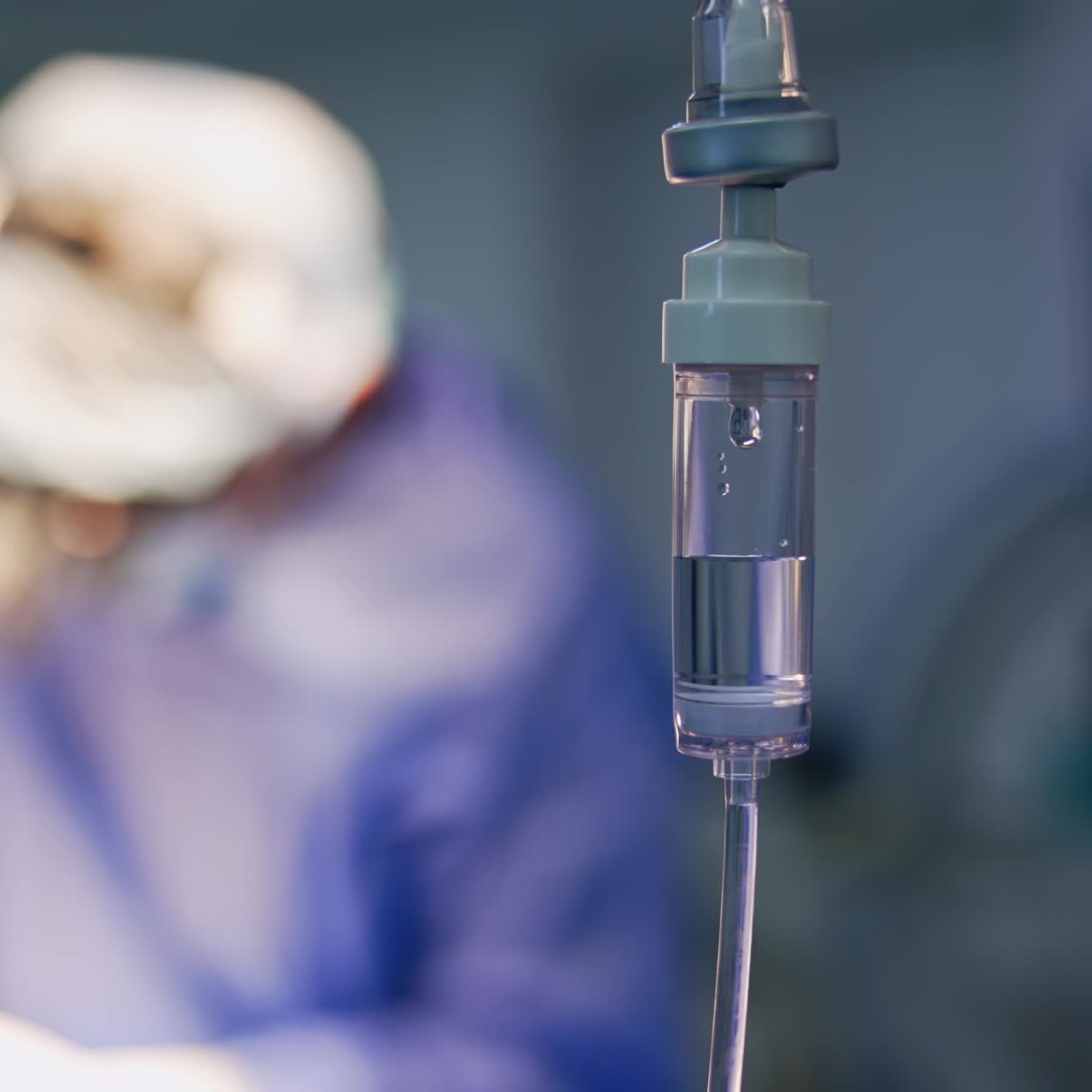 Contagocce riempito a metà con soluzione salina. Primo piano. Chirurghi che operano in sala operatoria sullo sfondo sfocato.