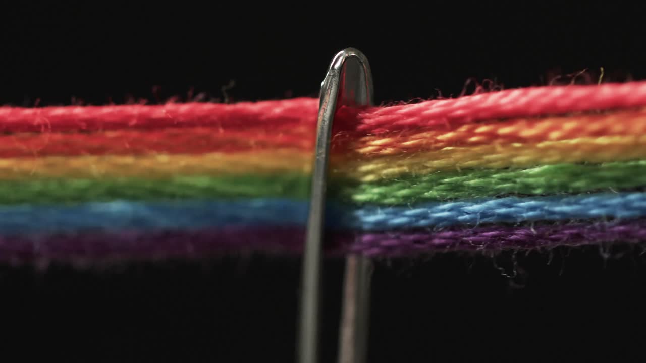 video de micro de hilos de color arco iris que pasan a través de la aguja con espacio de copia en fondo negro