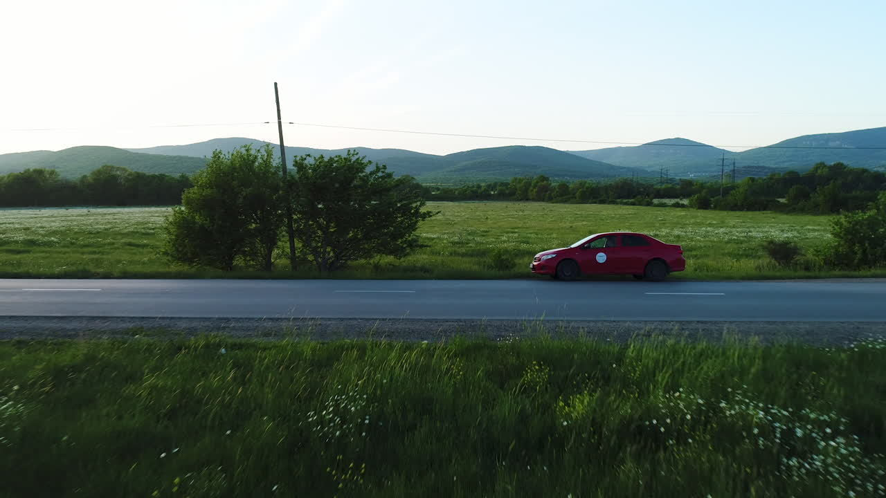 산과 이 있는 시골 도로에서 빨간 차