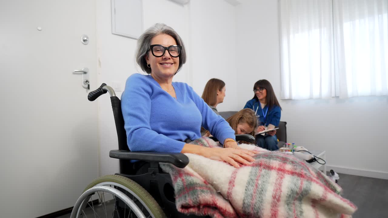 Donna anziana felice su sedia a rotelle sorride alla fotocamera con gli assistenti