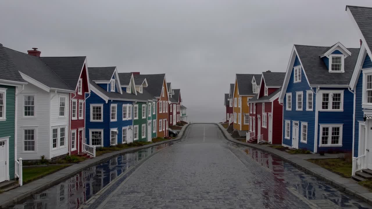 Rows of vibrant, colorful houses lining a wet cobblestone street, fading into the fog, create a serene and picturesque atmosphere, evoking a sense of tranquility and charm
