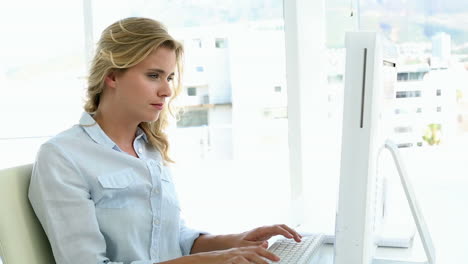 Casual-businesswoman-working-at-her-desk