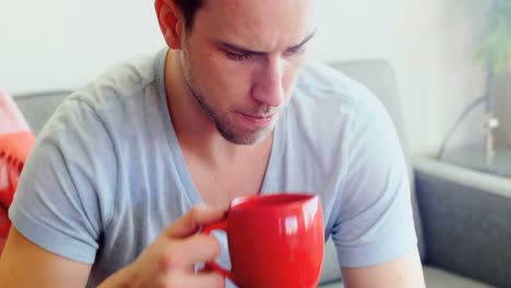 Man-using-mobile-phone-while-having-coffee-in-living-room-4k