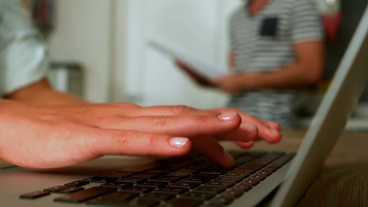 Woman using laptop while man reading newspaper
