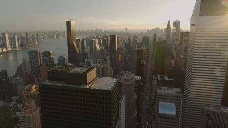 Aerial-panoramic-footage-of-buildings-in-city-at-sunset-time.-Wide-rive-in-background.-Manhattan,-New-York-City,-USA