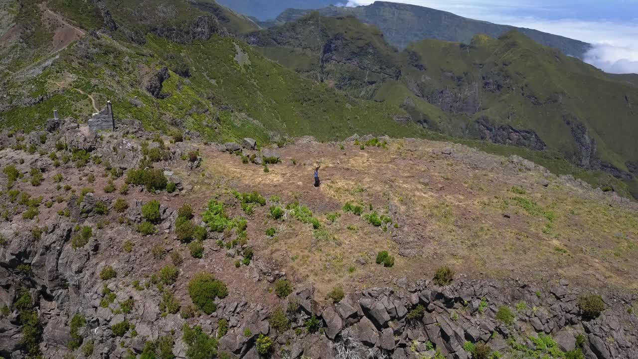 un hombre practicando sus habilidades de lucha wushu usando una espada tradicional de acero inoxidable en la cima de las montañas de madeira en portugal - fotografía aérea