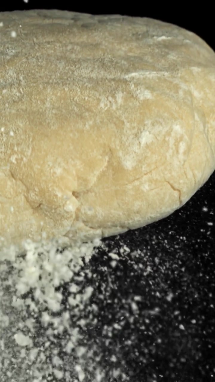 Slow Motion Close-up of Flour Falling onto Fresh Dough