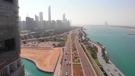 drone tilt down shot of a road in abu dhabi near the skyscrapers on a sunny day